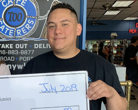 Fernando Mejia, the manager of Schmear Bagel & Cafe, was detained by ICE agents after spending 20 years in the country. He was previously the manager at Harbor Deli Too in Port Washington, where he is pictured receiving a check from the business improvement district.